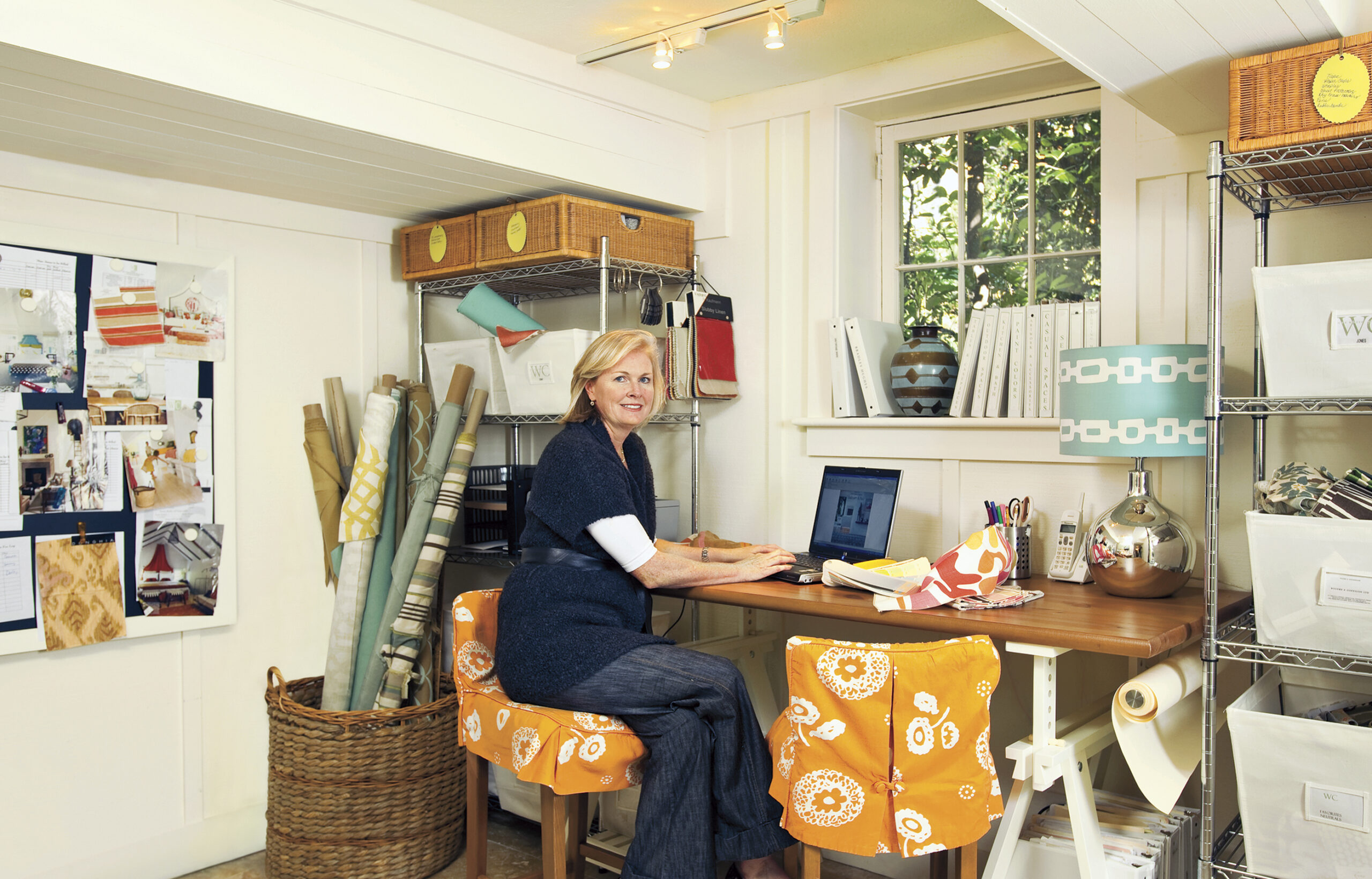A woman smiles sitting in a cottage-style basement home office space.