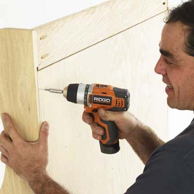 Man drilling pilot holes in bench.