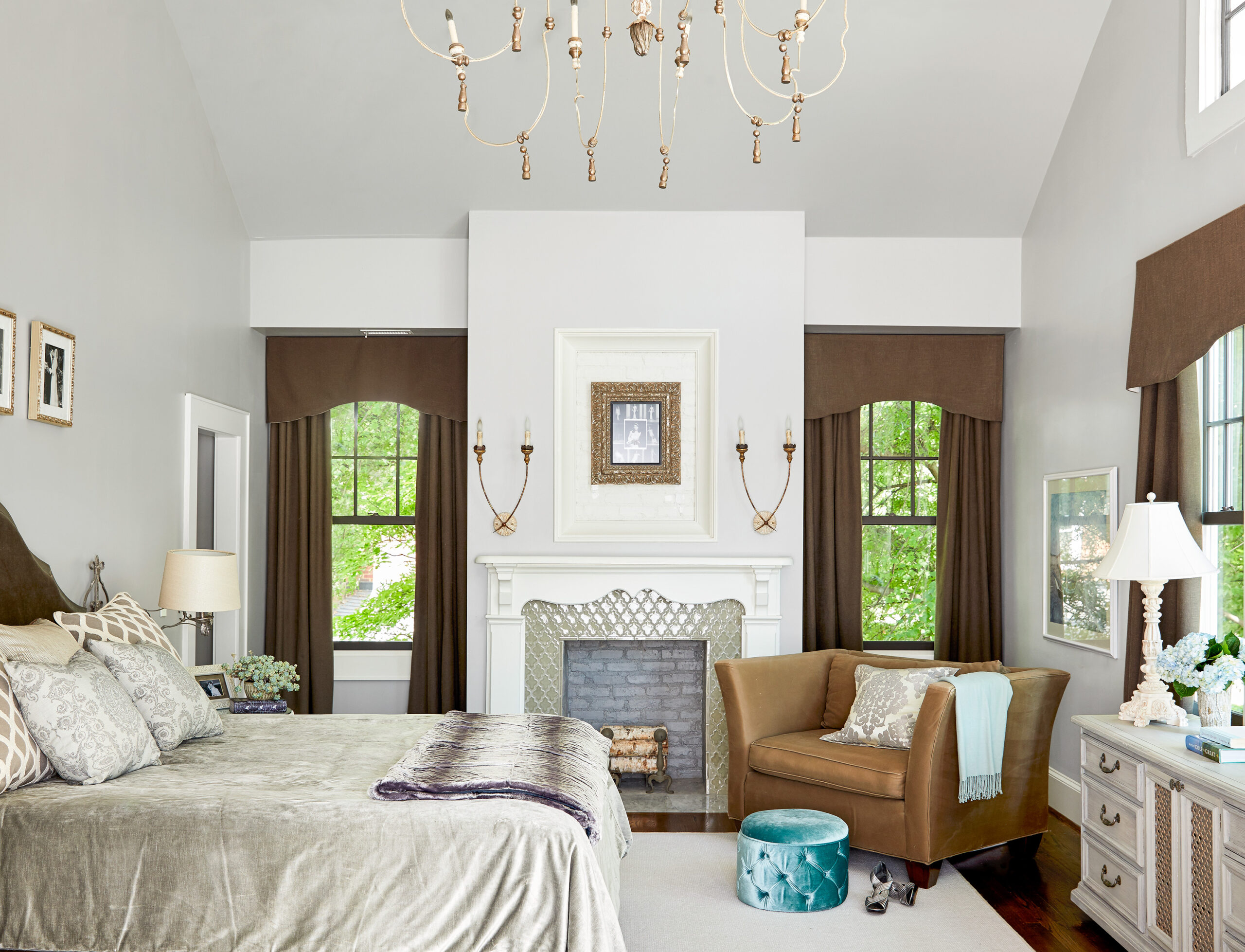 Master bedroom with brown curtains on three windows, a fireplace, and bed.