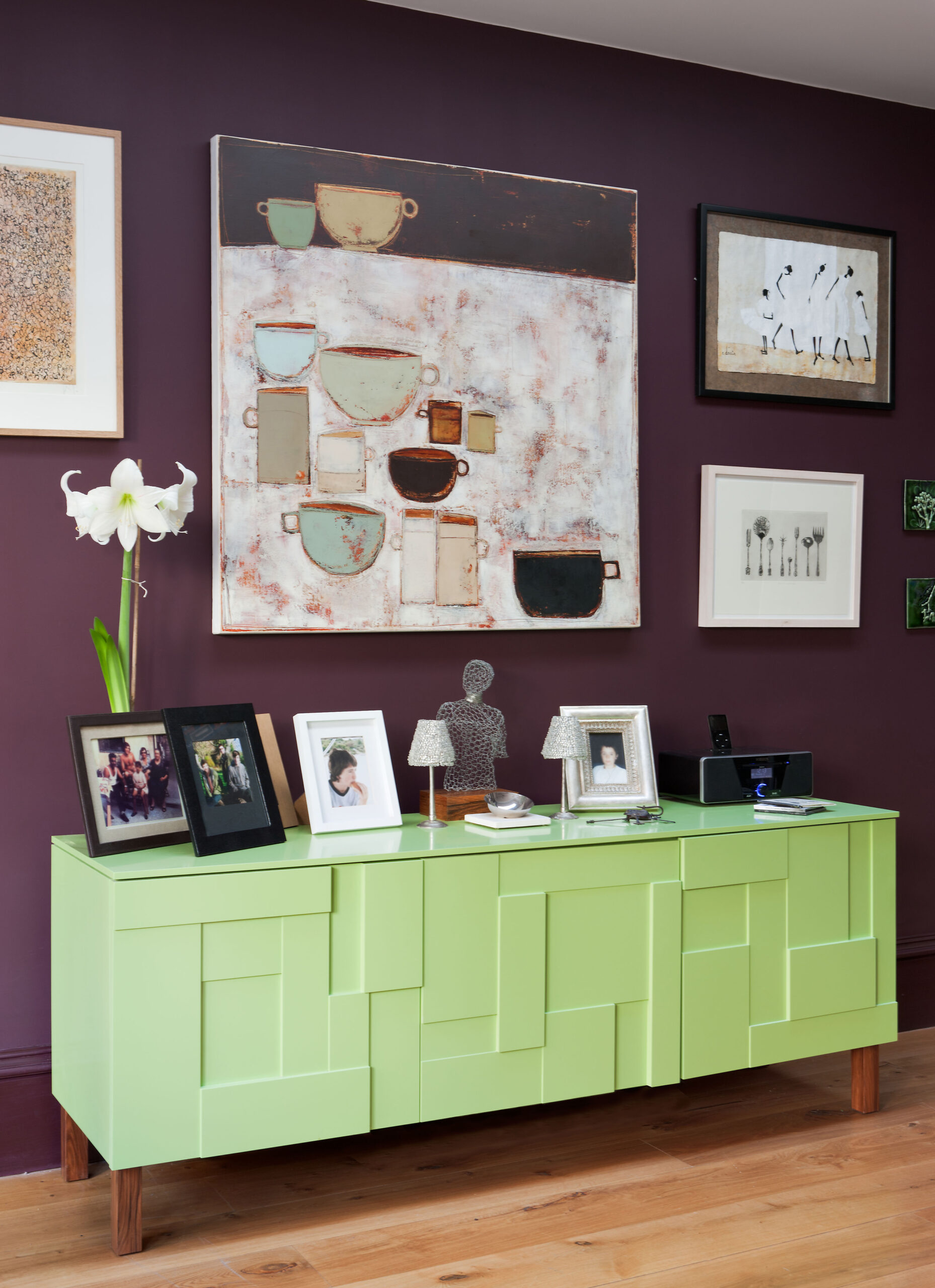 A wall full of art with a purple and red color scheme.