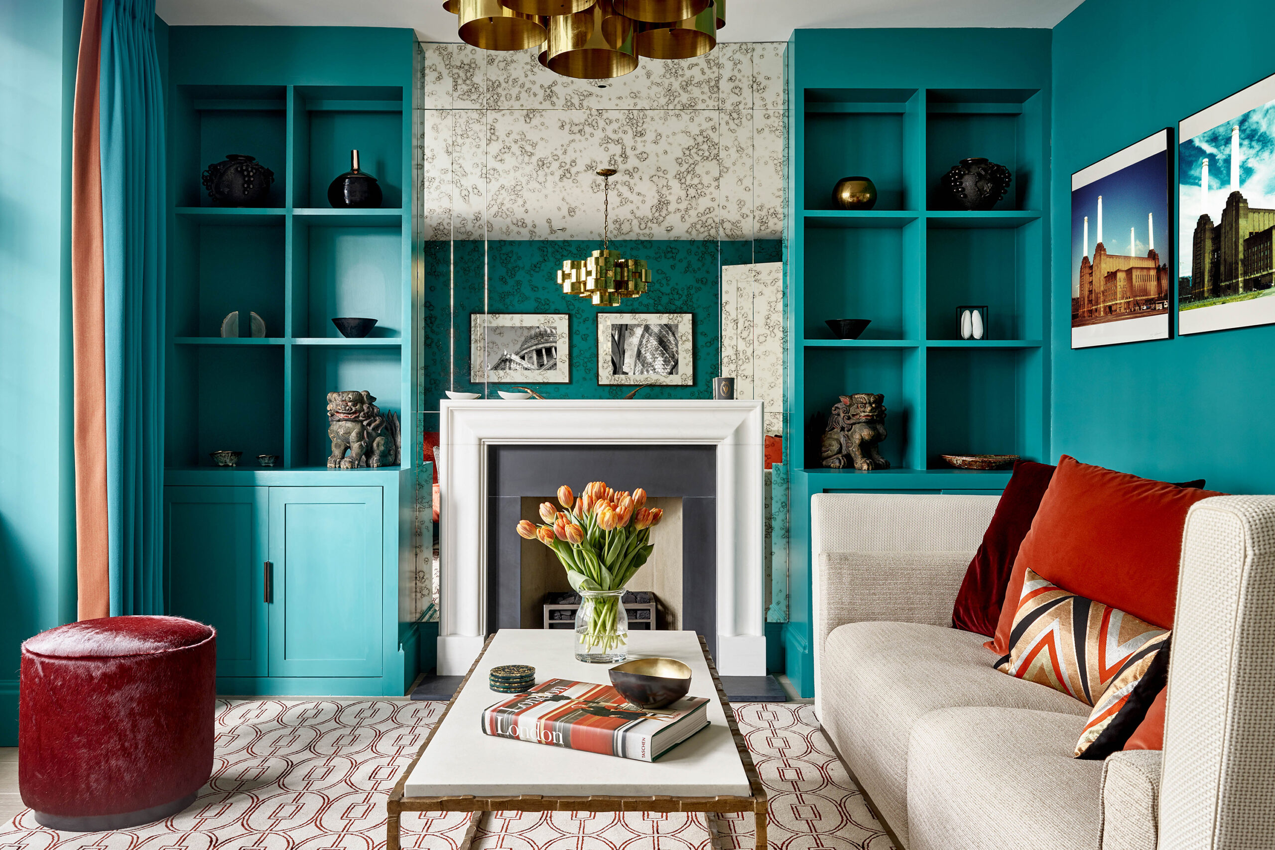 A sitting room with couches, tables and shelves with a blue and orange color scheme.