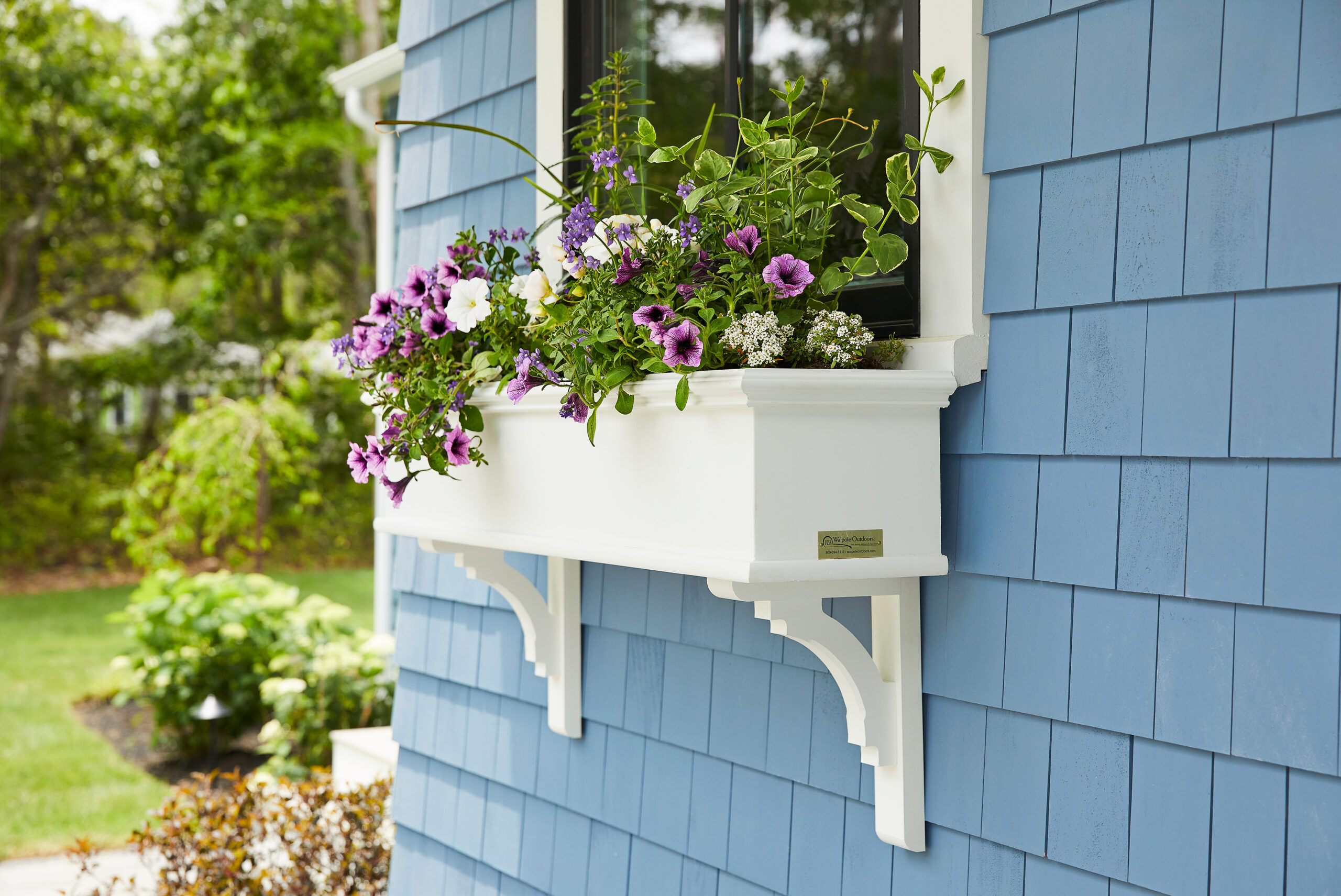Walpole Outdoors solid vinyl window boxes filled with flowers.